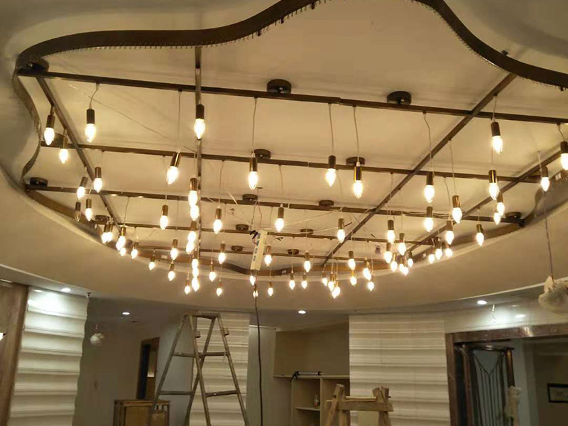 大型吊燈安裝：首先大致尺寸要測量好，確定位置；然后石膏板上鉆孔，然后埋設(shè)鐵件五金配件或者木條，用黏貼劑或者水泥漿將空洞的周邊補齊，等到差不多干燥了再接下來做。接著把鐵件或者木條固定，這是吊燈安裝的重要步驟，如果沒有固定好，使用壽命會受到影響。電線通過吊桿引入到燈芯里面，如果配套燈帶使用開關(guān)的，穿線的時候要注意線路的走向。最后就是燈罩、燈臂的安裝。用看、螺絲刀等工具將燈罩組裝好，安裝好后，通電試試就可以了，根據(jù)實際情況稍微調(diào)整下。