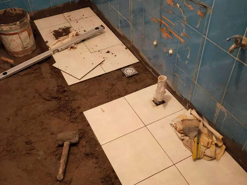 廁所地磚鋪貼維修：1、首先將選購好的瓷磚清潔干凈，并在水中浸泡2個(gè)小時(shí)以上，瓷磚的浸泡是為了能讓瓷磚充分的吸收水分，避免在鋪貼完成之后吸取材料中的水分，而影響瓷磚與地面的粘貼度，造成起空鼓、脫落等現(xiàn)象，開始鋪貼瓷磚之前需要從水中取出并將便面的水分擦去，以便鋪貼。 2、在開始瓷磚進(jìn)行鋪貼之前，需先在墻面上吊垂線，吊垂線是用來確定瓷磚與墻面的尺寸，再設(shè)置水平線，這樣能夠保證瓷磚鋪貼過程中保持橫平豎直的平整度。 3、在瓷磚鋪貼過程中需要以水平線為準(zhǔn)繩，設(shè)置木板將瓷磚支撐住，這樣是為了防止瓷磚在達(dá)到一定的粘著強(qiáng)度之前出現(xiàn)位移或下墜的現(xiàn)象。  4.、通常地磚的鋪貼都是由門窗邊或者陽臺(tái)開始的，保證從上到下，由左及右的順序行進(jìn)，先用水潤曾找平層，再用鏟子將水泥抹在瓷磚的背面，再將瓷磚貼在地面，再用橡膠錘輕輕敲擊瓷磚，使水泥充滿墻面與瓷磚之間的空隙，粘貼時(shí)要注意所使用的粘貼材料不能太稠，也不能太稀，太稠的話不容易攤開，太稀的話又不容易粘牢。 5、當(dāng)?shù)卮u鋪貼好之后，需要及時(shí)將表面的污漬清潔干凈，當(dāng)表面的污染比較嚴(yán)重時(shí)，可以使用10%濃度的稀鹽酸溶液來進(jìn)行清潔，如果選用稀鹽酸進(jìn)行清洗的話，最后一定要再用清水沖洗一遍。如果是瓷磚釉的話，清理完成之后還可在表面噴上一層薄薄的碧麗珠光亮劑，并且使用軟抹布再擦拭一遍，就能夠保持瓷磚表面的光澤度并且不容易受到污染。