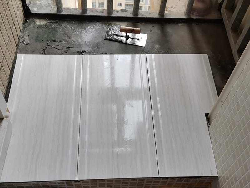 陽臺瓷磚鋪貼：準(zhǔn)備粘結(jié)劑前，瓷磚不應(yīng)浸水，但要用鋼絲刷除去磚背面的松散物質(zhì)，并用濕布抹去磚背的浮塵。然后按照生產(chǎn)商建議的比例將水或乳液放到攪拌桶中攪拌直至粘結(jié)劑均勻無結(jié)塊。初始攪拌后的粘結(jié)劑應(yīng)靜置在攪拌桶中，直到生產(chǎn)商推薦的熟化時間過后攪拌一下再使用。 在鋪壓瓷磚前，在瓷磚背面也批一薄層粘結(jié)劑。這種雙批法雖然用的材料和工時比較多，但卻能夠保證粘貼的質(zhì)量和耐久性。 在粘結(jié)劑量置晾時間內(nèi)，將準(zhǔn)備好的瓷磚鋪壓到位，垂直于梳理方向輕微搓動以排出磚下的空氣。鋪貼到位后用橡皮錘輕擊，用尺寸合適的十字定位架來調(diào)整表面平整度及接縫的平直。