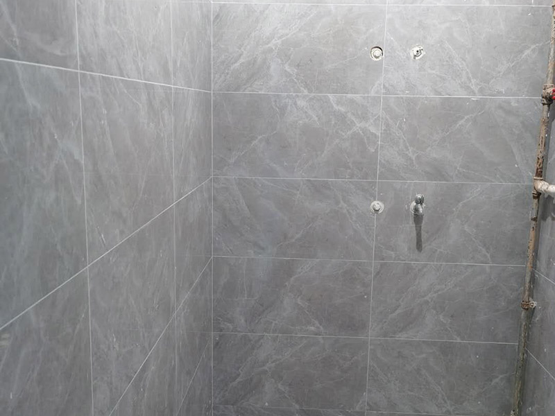 衛(wèi)生間貼磚施工：應(yīng)全部清理墻面上的各類污物，打掃干凈現(xiàn)場，特別是腳落里。用泥刀先批墻，后用水泥漿找平。這個工序很重要，確保底子平，防止貼后空鼓。墻面要刷防水涂料，防止貼后浸水，一般高度不低于1.8米，刷的時候會稍高一些。根據(jù)設(shè)計(jì)鋪貼圖樣的要求，確定排磚方案，用墨斗彈線，以減少施工損耗。把剛剛攪拌好的粘結(jié)劑漿料均勻的刮到墻上。瓷磚上墻將經(jīng)過預(yù)先清潔的瓷磚平整地鋪貼在粘結(jié)劑漿料基層上，使用橡膠錘將瓷磚拍實(shí)鋪平。施工過程中，可小幅度轉(zhuǎn)動瓷磚，使?jié){料與瓷磚背面充分接觸。專家建議在鋪貼時，隨機(jī)取下已鋪貼于基層上的瓷磚作檢查。確保漿料與瓷磚背面的充分接觸。 留縫大小調(diào)整根據(jù)瓷磚的尺寸，在磚與磚之間預(yù)留相應(yīng)尺寸的縫隙留待嵌縫?？捎醚篮灥认裙潭ǎ辰Y(jié)劑具有一定的可調(diào)整性，可對留縫的大小進(jìn)行調(diào)整。