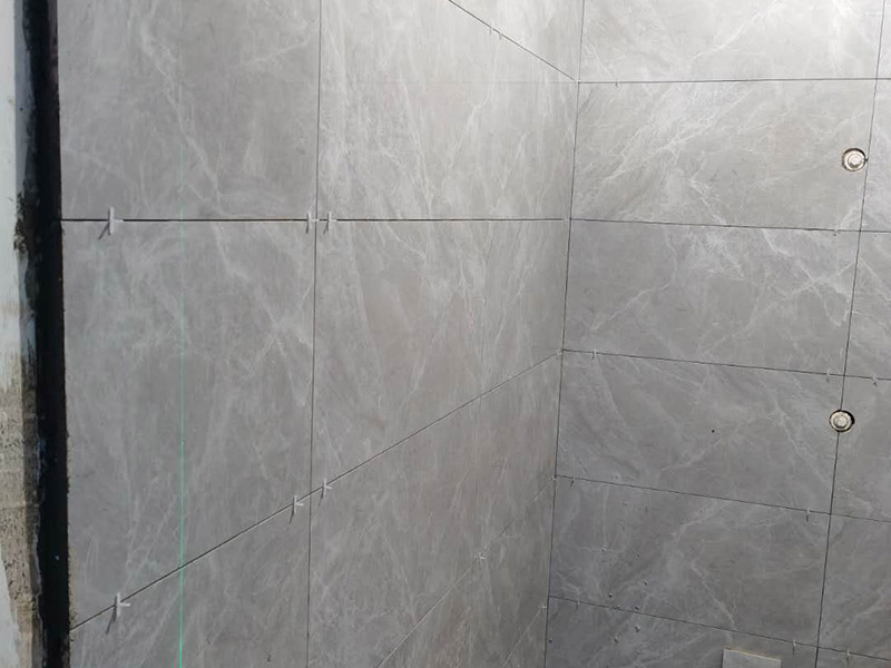 衛(wèi)生間貼磚施工：應(yīng)全部清理墻面上的各類污物，打掃干凈現(xiàn)場，特別是腳落里。用泥刀先批墻，后用水泥漿找平。這個工序很重要，確保底子平，防止貼后空鼓。墻面要刷防水涂料，防止貼后浸水，一般高度不低于1.8米，刷的時候會稍高一些。根據(jù)設(shè)計(jì)鋪貼圖樣的要求，確定排磚方案，用墨斗彈線，以減少施工損耗。把剛剛攪拌好的粘結(jié)劑漿料均勻的刮到墻上。瓷磚上墻將經(jīng)過預(yù)先清潔的瓷磚平整地鋪貼在粘結(jié)劑漿料基層上，使用橡膠錘將瓷磚拍實(shí)鋪平。施工過程中，可小幅度轉(zhuǎn)動瓷磚，使?jié){料與瓷磚背面充分接觸。專家建議在鋪貼時，隨機(jī)取下已鋪貼于基層上的瓷磚作檢查。確保漿料與瓷磚背面的充分接觸。 留縫大小調(diào)整根據(jù)瓷磚的尺寸，在磚與磚之間預(yù)留相應(yīng)尺寸的縫隙留待嵌縫?？捎醚篮灥认裙潭?，粘結(jié)劑具有一定的可調(diào)整性，可對留縫的大小進(jìn)行調(diào)整。