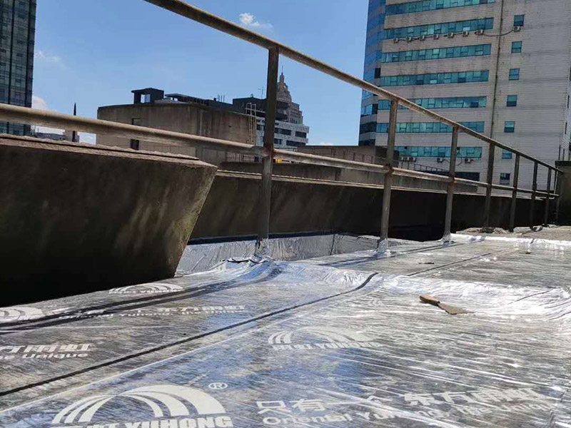 屋頂防水卷材鋪貼:1、由于設(shè)計(jì)要求屋面找坡層按2％坡度放坡，因此卷材鋪設(shè)時應(yīng)平行于屋脊自下而上的鋪貼，卷材搭縫必須嚴(yán)密，縫口應(yīng)順?biāo)鞣较虼罱?，其寬度不?yīng)小于50mm，上下屋接縫應(yīng)左右錯開250mm，在鋪大面積防水卷材之前，應(yīng)將檐溝，管道口、雨水口處的附加防水布鋪好后由屋頂?shù)牡吞幭蚋咛庍M(jìn)行大面積的鋪貼。 2、屋頂卷材遇到女兒墻時，應(yīng)將卷材沿墻上卷，高度應(yīng)低于250mm，然后固定在墻上預(yù)埋的木磚和木塊上，并用1：3水泥砂漿做坡水。 3、凡管道等伸出屋面的構(gòu)件必須在屋頂上開孔時，為了防漏水應(yīng)將卷材向上翻起，抹以水泥砂漿或再蓋上鍍鋅鐵皮起擋水作用，泛水高度不超過200mm。 防水材料卷材層應(yīng)粘結(jié)牢固，無空鼓、損傷、滑移，翹邊、起泡、皺折等缺陷。防水工程施工完畢后，必須作蓄水試驗(yàn)合格后開始進(jìn)行下道工序。