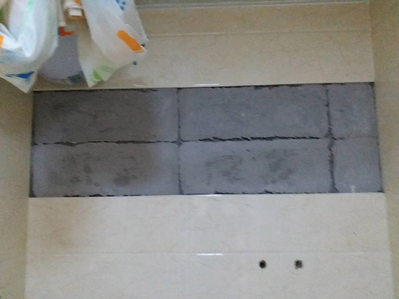 墻面瓷磚脫落修補：首先將脫落的磚四周用裁紙刀的刀背咔嚓一遍，將勾縫劑或水泥等附著物清理掉，漏出瓷磚的原邊。同時需要清理的，還有墻上與脫落瓷磚相連的瓷磚邊緣。當(dāng)然，用刀刃也可以，但比較毀刀片。然后用稍微潮濕的抹布擦干凈瓷磚背面的浮灰，最好用鋼絲球來刷一遍瓷磚背面再擦，目的是去掉可能存在的脫模劑。接著就是清理墻面的水泥砂漿層，將松動的碎塊去掉，然后也整體用抹布擦一遍。將玻璃膠用裁紙刀切掉密封出口，如果有槍嘴就擰上槍嘴，沒有也可以直接用。如果墻上的水泥砂漿四周有縫隙，可在縫隙內(nèi)也擠些玻璃膠，這樣可以連接那些沒掉的瓷磚，防止附近的瓷磚將來也脫落。然后將這背面抹膠的瓷磚貼回原處，磚與磚之間插上牙簽來留縫隙。再用手指抹玻璃膠到磚與磚之間的縫隙里。