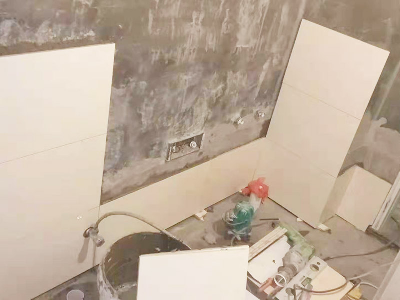 衛(wèi)生間墻面貼磚：首先應除去基層表面的污垢，油漬，浮灰;除去基層上所有涂料層，膩子層;如果基層未能達到平整度要求，需對基層進行預先的找平處理。鋪貼瓷磚前需事先找好垂直線，以此為基準鋪貼的瓷磚高低均勻、垂直美觀;此外，施工前在墻體四周需彈出標高控制線，在地面彈出十字線，以控制地磚分隔尺寸。對瓷磚的色彩、紋理、表面平整等進行嚴格的挑選，然后按照圖紙要求預鋪。對可能出現(xiàn)的尺寸、色彩、紋理誤差等進行調(diào)整、交換，直至達到最佳效果。 調(diào)制粘結劑：加水后將粘結劑漿料攪拌至潤滑均勻，無明顯塊狀或糊狀結塊，攪拌后的漿料靜置5-10分鐘后再稍加攪拌1-2分鐘即可使用。 將瓷磚平整地鋪貼在基層上，使用橡膠錘將瓷磚拍實鋪平。施工過程中，可小幅度轉動瓷磚，使?jié){料與瓷磚背面充分接觸。